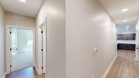 This well-appointed single-story home in Indianapolis, IN offers a thoughtfully designed layout across three bedrooms and two full bathrooms. The open-concept kitchen and living area serves as the heart of the home, featuring dark-stained shaker cabinetry, white quartz countertops, a subway tile backsplash, stainless steel appliances, and a central island with pendant lighting — all set atop warm luxury vinyl plank flooring. The living room is bright and spacious, with multiple large windows framing lush outdoor views and a sleek ceiling fan overhead, along with crown molding that adds a refined touch. A glass door provides direct access to an outdoor deck. The primary bedroom offers generous proportions with plush carpet and natural light. Additional bedrooms feature carpet flooring, ceiling fans, and windows with outdoor views. Both bathrooms showcase dark-framed mirrors, dark hardware, wood-toned vanities, and white quartz surfaces. The primary bath includes a double-sink vanity, while the secondary bath features a tiled tub-shower combo. A hallway with barn-style doors and two closets rounds out the functional layout. The neutral color palette and modern hardware selections create a cohesive, contemporary aesthetic throughout.