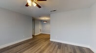 This single-floor residence showcases a clean, modern aesthetic carried consistently throughout every room. Rich wood-look vinyl plank flooring flows seamlessly across the living areas, bedrooms, and hallways, lending warmth and cohesion to the space. Walls are painted in a soft, calming blue-gray tone that complements the bright white trim and baseboards found throughout.

The open living and dining areas are generously proportioned, each equipped with ceiling fans fitted with integrated lighting. Natural light filters in through slatted window blinds, creating an airy, welcoming atmosphere. A pendant light fixture adds a decorative accent in the dining area.

The galley-style kitchen is thoughtfully designed with white shaker cabinetry, gray quartz countertops, a subway tile backsplash, and stainless steel appliances including a refrigerator, electric range, and over-the-range microwave. An undermount sink with a brushed nickel faucet completes the functional and stylish workspace.

The bedrooms are well-sized, each featuring ceiling fans and ample natural light. One bedroom includes a walk-in closet, offering generous storage. The bathroom is finished with marble-look tile flooring, a white tiled tub-shower combination, a vanity with brushed gold hardware, and neutral countertops, achieving a clean and elegant look. The overall layout is practical and efficient, making excellent use of the available space.