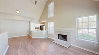 Located at 2802 Cheval St in Orlando, FL, this two-story, three-bedroom, two-bathroom home offers a well-organized and functional layout across its two levels. The main living area is anchored by a dramatic vaulted ceiling that soars overhead, creating an airy, open atmosphere. Large windows allow generous natural light to fill the space, complementing the light wood-tone flooring. A tiled fireplace with a clean white mantle serves as a focal point in the living room, adding warmth and character. The kitchen flows seamlessly from the living area and features white cabinetry, light quartz countertops with a peninsula and integrated sink, a gray subway tile backsplash, and a full suite of stainless steel appliances including a range, over-the-range microwave, dishwasher, and refrigerator. The three bedrooms are finished with plush carpeting and ceiling fans, offering comfortable, private retreats. The primary bedroom includes dedicated closet space and access to a well-appointed bathroom with a vanity, light wood-tone flooring, and a clean, neutral palette. The secondary bathroom features a tiled tub-shower combination with chrome fixtures. A hallway connects the upper-level rooms, and two staircases facilitate convenient movement throughout the home. The overall aesthetic is clean, modern, and move-in ready.