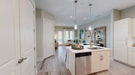 Located along Sam Houston Parkway in Houston, TX, this one-bedroom, one-bathroom residence offers a thoughtfully designed open-concept layout that maximizes every square foot. Light wood-look flooring flows throughout the main living areas, creating a cohesive and contemporary aesthetic.

The kitchen serves as a central hub of the home, featuring crisp white cabinetry extending to the ceiling, quartz countertops, a tile backsplash, and a full suite of stainless steel appliances including a range, microwave, refrigerator, and dishwasher. A kitchen island with a built-in sink and pendant lighting above adds both functionality and style.

The open living area is bathed in natural light from large windows and a glass door that offers outdoor views and direct access, creating an airy, inviting atmosphere. The bedroom is carpeted for comfort, includes a ceiling fan, and features large windows with outdoor views. It connects directly to a well-sized bathroom appointed with granite countertops, an elongated vanity, and tile flooring.

A generously proportioned walk-in closet with multiple hanging rods and shelving provides ample storage. The overall design balances modern finishes with a warm, neutral palette throughout.