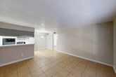 Located at 1000 Greens Road in Houston, TX, this one-bedroom, one-bathroom unit offers a practical and well-organized layout across a single floor. The combined kitchen and living area forms the heart of the home, with light-toned tile flooring running throughout and a pendant light fixture above the open pass-through that connects the two spaces. The living room receives natural light through a large front-facing window positioned beside the entry door, lending the area a bright and welcoming feel. The kitchen is efficiently designed with light gray cabinetry, white countertops, a stainless steel sink, and black appliances including a refrigerator, range, and dishwasher — offering ample functionality within a compact footprint. The bedroom is a generously proportioned space featuring two windows that allow for natural light and cross-ventilation, complemented by a ceiling fan with integrated lighting. It provides direct access to a dedicated walk-in closet outfitted with wire shelving on multiple walls, offering practical storage capacity. The bathroom is clean and straightforward, featuring a full tub-shower combination with tiled surround. Consistent tile flooring throughout the unit ties the spaces together with a cohesive, easy-to-maintain aesthetic.