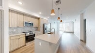 Located at 100 S 48th St in Phoenix, AZ, this well-appointed 2-bedroom, 2-bathroom residence offers a clean, modern aesthetic throughout. Light wood-style flooring flows consistently across the open floor plan, creating a bright and cohesive feel. The open-concept kitchen and living area serves as the heart of the home, featuring a large center island with an undermount sink, quartz countertops, light wood cabinetry, a marble-style tile backsplash, stainless steel appliances, and stylish pendant lighting. The primary bedroom is generously sized, filled with natural light from large windows overlooking the surrounding neighborhood, and includes a ceiling fan and access to a private balcony. The en-suite primary bathroom offers a glass-enclosed shower with marble-style tile, a single vanity with quartz countertop, and direct access to a walk-in closet with built-in shelving. The second bedroom is bright and well-proportioned with its own access to a closet. The second bathroom features a tub-shower combination with matching marble-style tile surround and a single vanity. Two dedicated closets provide ample storage throughout. The overall ambiance is clean, contemporary, and light-filled.