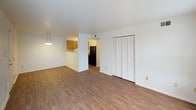 This single-story unit is designed with a practical, open layout highlighted by consistent wood-style flooring that runs throughout the living spaces and bedrooms. The living area is generously sized, featuring white walls, clean lines, and a built-in closet with louvered bifold doors for convenient storage. A pendant light fixture marks the transition into the adjacent kitchen, which is equipped with warm-toned wood cabinetry, light countertops, a black electric range, a stainless steel sink, and overhead pendant lighting — creating a functional and efficient cooking space.

The bedrooms each feature ceiling fans with light fixtures and windows that allow natural light to filter in, contributing to a bright and airy feel. Closet space is available in the bedrooms, and the neutral white walls provide a versatile backdrop. The bathroom includes a wood-vanity with a white countertop, a mirrored medicine cabinet, a wall-mounted light fixture, and a grab bar for added accessibility.

The main living area also includes a glazed entry door alongside an additional window, allowing ample natural light into the space. Throughout, the unit maintains a clean, understated aesthetic with white walls, simple trim, and consistent flooring that ties each area together cohesively.