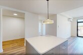 Located at 873 Communipaw Avenue in Jersey City, NJ, this thoughtfully designed 2-bedroom, 2-bathroom residence offers a clean, modern aesthetic throughout its well-proportioned single-floor layout. Warm hardwood flooring flows seamlessly across the living areas, bedrooms, den, and hallway, creating a cohesive and inviting atmosphere.

The open-concept kitchen and living room serve as the heart of the home. The kitchen is outfitted with sleek grey cabinetry extending to the ceiling, stainless steel appliances including a range, over-the-range microwave, dishwasher, and refrigerator, complemented by a white tile backsplash and light countertops. A pendant light fixture adds a contemporary touch above the kitchen island.

Both bedrooms are bright and airy, featuring large black-framed windows that frame outdoor views and allow generous natural light to fill the rooms. The spacious primary bedroom offers a comfortable retreat. Three closets provide excellent storage throughout.

The two bathrooms are finished with clean, neutral tile work — one showcasing a full soaking tub with floor-to-ceiling tile surround, and the other featuring a glass-enclosed walk-in shower. A dedicated laundry area and a flexible den add further functionality. The space also includes a private balcony, ideal for outdoor enjoyment.