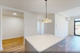 Located at 873 Communipaw Avenue in Jersey City, NJ, this thoughtfully designed 2-bedroom, 2-bathroom residence offers a clean, modern aesthetic throughout its well-proportioned single-floor layout. Warm hardwood flooring flows seamlessly across the living areas, bedrooms, den, and hallway, creating a cohesive and inviting atmosphere.

The open-concept kitchen and living room serve as the heart of the home. The kitchen is outfitted with sleek grey cabinetry extending to the ceiling, stainless steel appliances including a range, over-the-range microwave, dishwasher, and refrigerator, complemented by a white tile backsplash and light countertops. A pendant light fixture adds a contemporary touch above the kitchen island.

Both bedrooms are bright and airy, featuring large black-framed windows that frame outdoor views and allow generous natural light to fill the rooms. The spacious primary bedroom offers a comfortable retreat. Three closets provide excellent storage throughout.

The two bathrooms are finished with clean, neutral tile work — one showcasing a full soaking tub with floor-to-ceiling tile surround, and the other featuring a glass-enclosed walk-in shower. A dedicated laundry area and a flexible den add further functionality. The space also includes a private balcony, ideal for outdoor enjoyment.