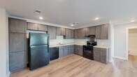 Located at 933 Lincoln Avenue in Cincinnati's 45206 neighborhood, this single-story, three-bedroom, two-bathroom home offers a thoughtfully designed layout with consistent, modern finishes throughout. Light wood-tone flooring runs seamlessly across every room, complemented by neutral gray-toned walls that create a clean, cohesive aesthetic.

The kitchen is a functional centerpiece, featuring dark gray shaker-style cabinetry extending to the ceiling for ample storage, light quartz countertops, a stainless undermount sink, and a full suite of black appliances including a refrigerator, dishwasher, and electric range. Recessed lighting illuminates the space effectively.

Each of the three bedrooms is finished with the same warm wood flooring and neutral walls. The bedrooms feature ceiling fans with light fixtures and windows with blinds that invite natural light and outdoor views. The primary bedroom benefits from dual windows, enhancing brightness and airflow.

Both bathrooms are finished cleanly, with one featuring a full tub-shower combination with white subway tile surround and chrome fixtures. A dedicated laundry area with an in-unit washer is tucked neatly behind a paneled door, adding everyday convenience. Two hallways connect the layout efficiently, and the overall design prioritizes a bright, move-in ready environment.