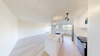 Located on the fifth floor at 3030 Prospect St in Burlington, Ontario, this thoughtfully renovated one-bedroom, one-bathroom unit offers a clean, modern aesthetic throughout. Light-toned hardwood flooring flows seamlessly across the entire space, creating a bright and cohesive feel.

The open kitchen and living area serves as the heart of the unit. The kitchen is outfitted with crisp white cabinetry, glossy upper shelving, quartz countertops, stainless steel appliances including a refrigerator, electric range, and built-in microwave, and a contemporary multi-directional pendant light fixture that adds a stylish focal point.

The living room is generously sized, bathed in natural light, and features baseboard heating. A private balcony extends off the living area, offering elevated views of the landscaped grounds, mature trees, and the surrounding Burlington neighbourhood under open skies.

The bedroom is a comfortable, well-proportioned room with a large window framing lush green treetop views, a flush-mount light fixture, and baseboard heating. A sliding-door closet within the bedroom houses a stacked in-suite washer and dryer, a highly practical feature.

The bathroom is finished in clean white tile, featuring a soaker tub with overhead shower, white countertop vanity, and chrome fixtures. The overall ambiance of the unit is fresh, minimal, and move-in ready.