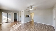 Located at 305 W Baker Rd in Baytown, TX, this single-story home offers a functional and comfortable layout with two bedrooms, two bathrooms, and a well-defined arrangement of living spaces. Wood-look flooring runs throughout the home, complemented by soft gray walls and white trim, creating a clean, cohesive aesthetic.

The open living and dining area is bright and welcoming, featuring a ceiling fan with light fixture and natural light that pours in through a sliding glass door offering outdoor views. A pass-through counter connects this space to the kitchen, which is equipped with black appliances including an electric range and refrigerator, white cabinetry, and access to a dedicated pantry for additional storage.

Both bedrooms are comfortable in scale, each with wood-look flooring, natural light from windows with blinds, and ceiling fans. The primary bedroom is notably spacious and includes direct access to a walk-in closet with built-in shelving and hanging rods. The second bedroom also features closet access. Each bathroom includes a full tub-shower combination with clean white surrounds and matching flooring.

A hallway connects the main living areas to the bedrooms, maintaining a practical flow throughout the home. Textured ceilings and consistent finishes tie the space together for a neat, move-in-ready presentation.