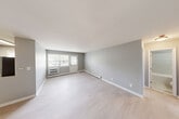 Located at 211 Hawthorne Ave in Central Islip, NY, this well-appointed one-bedroom, one-bathroom residence offers a thoughtfully designed single-floor layout. The spacious living room is bathed in natural light through double doors and large windows, showcasing light wood-tone flooring and neutral gray walls that create a clean, modern aesthetic. Baseboard heating runs throughout, ensuring year-round comfort. The combined kitchen and dining area features dark cabinetry with ample storage, a marble-style backsplash, light countertops, and a full suite of appliances including a gas range, microwave, dishwasher, and refrigerator, all illuminated by a skylight-style ceiling fixture and a bright window. The generously sized bedroom offers two windows that bring in abundant natural light, continuing the same light flooring and soft gray palette. The bathroom is finished with large-format white subway tiles surrounding a soaking tub and shower combination, complemented by brushed nickel fixtures and a white vanity. Three closets provide excellent storage throughout the unit. A private balcony overlooks the landscaped community grounds, parking area, and surrounding neighborhood, offering a pleasant outdoor retreat.