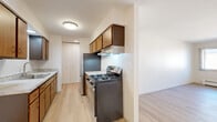 This two-bedroom, one-bathroom single-floor residence at 1674 Shawano Ave offers a well-organized layout with a comfortable sense of space throughout. Light-toned luxury vinyl plank flooring runs through the main living areas, lending a clean and cohesive look, while soft carpet adds warmth to the bedrooms.

The galley-style kitchen is efficiently designed with warm wood cabinetry in both light and dark finishes, a stainless steel refrigerator, a gas range with overhead ventilation, a double stainless steel sink with a granite-look countertop, and a dishwasher. The kitchen opens directly into the combined dining area, creating a practical and connected space for everyday living.

The family room is generously proportioned, featuring large sliding windows that invite natural light and provide exterior views. Baseboard heating is present throughout the unit, ensuring year-round comfort.

The primary bedroom offers a comfortable footprint with carpeted flooring, a sliding window, and notable storage with access to two closets, including a spacious walk-in closet with built-in shelving and hanging rods. The second bedroom is similarly carpeted and well-lit with a window.

The bathroom is clean and straightforward, featuring a tiled tub-shower surround, a granite-topped vanity, and light wood-tone flooring. A hallway connects all rooms, and three total closets throughout the unit provide ample storage.