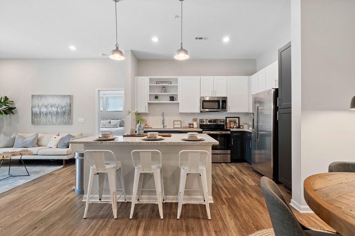 Kitchen with white and dark cabinetry, speckled granite countertops, white subway tile backsplash, stainless steel appliances, and hard surface flooring - Avalon at Palisades