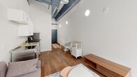 Located at 601 Penn St, Unit 409 in Reading, PA, this one-bedroom, one-bathroom unit offers an efficient yet thoughtfully designed layout with standout industrial-modern character. The open living and kitchen area features striking soaring ceilings with exposed steel beams and ductwork painted in deep charcoal, creating a loft-like aesthetic that adds vertical drama to the compact footprint. Warm hardwood flooring runs throughout, anchoring the clean, bright interiors defined by crisp white walls.

The kitchen is well-appointed with white shaker cabinetry, light countertops, a stainless steel refrigerator, range, and dishwasher, alongside a single-basin sink — delivering full functionality in a streamlined galley-style arrangement. Circular wall sconces provide soft accent lighting along the main corridor, adding a modern touch.

The bedroom is generously proportioned relative to the overall layout, benefiting from a large picture window that invites natural light and frames views of the surrounding cityscape. The exposed ceiling detail continues here, reinforcing the unit's industrial character.

The bathroom is finished with marble-look tile flooring, gray cabinetry with a white countertop vanity, and a full-size soaking tub and shower combination, offering a clean and functional space.