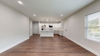 Located at 2 Towpath Rd in Halfmoon, NY, this single-floor, 2-bedroom, 2-bathroom home offers a clean, modern aesthetic throughout. Rich hardwood-style flooring flows seamlessly across the main living areas, complemented by neutral gray walls and crisp white trim that create a bright, contemporary atmosphere.

The open-concept kitchen is a standout feature, boasting white shaker cabinetry, quartz countertops, a large center island with an undermount sink, stainless steel appliances, and bold pendant lighting. The adjacent living area is well-proportioned and bathed in natural light from a large window with neighborhood views.

The spacious primary bedroom includes a generous closet with built-in wire shelving systems, providing ample storage. The second bedroom is equally well-sized with a built-in closet. Both bathrooms are finished with marble-look tile flooring and white fixtures; the primary bath features a rich dark-wood double vanity with a wide mirror and modern lighting.

Recessed lighting is featured throughout the home, enhancing the clean lines of each room. The attached garage is equipped with an automatic opener and a wall-mounted mini-split unit. The home's thoughtful layout and high-quality finishes make it a well-appointed residence in the Halfmoon area.
