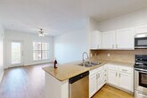 Located at 2104 Canal St in Houston's 77003 zip code, this one-bedroom, one-bathroom residence offers a well-designed single-floor layout. The open-concept kitchen flows seamlessly into the combined dining and living area, creating a connected and functional living space. The kitchen is outfitted with white shaker-style cabinetry, granite-style countertops, a peninsula with a stainless steel sink, a tile backsplash, and a full suite of stainless steel appliances including a refrigerator, range, over-the-range microwave, and dishwasher. Warm hardwood-style flooring runs throughout the main living areas, complemented by ceiling fans that add comfort and airflow. The living area benefits from multiple windows that invite natural light and provide outdoor views. The bedroom is comfortably sized, finished with plush carpet, a ceiling fan, and windows overlooking the surroundings, along with access to ample closet space. The bathroom features a vanity with matching granite-style countertop, a large mirror, and clean, neutral finishes. Additional highlights include a dedicated laundry area and a welcoming entryway with built-in storage cabinetry. The overall aesthetic is clean, bright, and move-in ready.