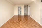 Located at 140 Carlton Street, this one-bedroom, one-bathroom unit offers a thoughtfully organized layout across a single floor. The living room is a bright, open space anchored by gleaming parquet wood flooring in a classic basket-weave pattern, which carries throughout the unit. A large window frames sweeping city and treetop views, filling the room with abundant natural light and creating an airy atmosphere. The entrance hallway features a sliding door, providing convenient access and a clean transition into the main living area. The bedroom continues the parquet flooring and benefits from its own generous window, offering similar scenic outdoor views and ample daylight. The kitchen is efficiently designed with white cabinetry extending to the ceiling for maximum storage, a double-coil electric range, a full-size refrigerator, a stainless steel sink, and light-toned ceramic tile flooring. The bathroom is finished in a clean, all-white palette, featuring a tiled shower-tub combination with a full white tile surround, a pedestal-style vanity with sink, a toilet, and classic mosaic tile flooring. Overall, the unit presents a clean, functional, and well-lit living environment with consistent finishes throughout.