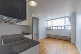 Located at 1005 Lansdowne Avenue in Toronto's vibrant Bloordale Village neighbourhood, this compact studio unit offers a well-designed and efficiently utilized single-floor layout. The space is characterized by warm-toned hardwood flooring that runs throughout the main living area, complemented by bright white walls that enhance the sense of openness.

The kitchen is thoughtfully equipped with a full suite of stainless steel appliances, including a refrigerator, built-in oven, ceramic cooktop, over-the-range microwave, and dishwasher. Crisp white cabinetry with sleek hardware provides ample storage, while the dark countertops offer a modern contrast. Recessed and flush-mount ceiling lighting keeps the kitchen area well-lit.

The main living area benefits from a large floor-to-ceiling window that frames views of the surrounding Toronto cityscape, allowing generous natural light to fill the room. A baseboard heating unit runs beneath the window, ensuring year-round comfort. The room offers a clean, open canvas well-suited for flexible living arrangements.

The bathroom is finished with neutral large-format tiles on both the floor and walls, and features a wall-mounted vanity with a vessel sink, a toilet, and a large mirror with recessed lighting above, lending a polished, contemporary feel to the space.