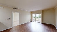 This thoughtfully designed one-bedroom, one-bathroom unit offers a comfortable and efficient layout across a single floor. The open-concept living and dining area is finished with warm hardwood-style flooring, crown molding, and neutral-toned walls that create a bright, welcoming ambiance. A large sliding glass door floods the space with natural light and opens directly onto a private patio, where lush greenery provides a pleasant outdoor retreat. The front entryway features a classic paneled door with recessed lighting overhead. The kitchen is well-equipped with honey-toned wood cabinetry offering ample storage, granite-style countertops, a breakfast bar peninsula, and a full suite of white appliances including a range, microwave, and refrigerator. Recessed lighting enhances the kitchen's functionality. The spacious primary bedroom features plush carpeting, two windows that invite natural light and outdoor views, and a dedicated closet for storage. The bathroom is finished with tile flooring, a warm wood vanity with dark countertop, a framed mirror with bar lighting above, and a tub-shower combination enclosed by sliding glass doors. Crown molding details are carried throughout the living areas, tying the space together with a cohesive, polished finish.