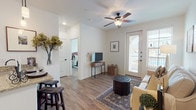 This single-story residence offers a thoughtfully designed layout that balances functionality and comfort throughout its well-connected rooms. The entry opens directly into a bright living area finished with wood-look flooring, a ceiling fan, and a glass-paneled door that allows natural light to filter in alongside views of an outdoor balcony. Neutral white walls and recessed lighting create a clean, airy atmosphere throughout the common areas.

The kitchen is a standout feature, showcasing dark espresso cabinetry that reaches toward the ceiling, stainless steel appliances, and a granite-topped peninsula with pendant lighting overhead—ideal for casual dining or meal prep. The peninsula connects seamlessly to a dedicated dining area, reinforcing the open-concept flow.

The bedroom is a serene retreat, carpeted for warmth and equipped with a ceiling fan, natural light from sizable windows, and direct access to the bathroom. The bathroom features granite countertops with dark cabinetry, wood-look flooring, and a tiled soaking tub-shower combination with classic mosaic tile accents.

A dedicated laundry area accommodates a full-sized washer and dryer side by side, with shelving above for added storage. Throughout the space, a consistent palette of neutral tones and warm wood-look flooring ties each room together cohesively.