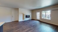 This single-floor residence offers a thoughtfully designed layout that balances functionality and comfort throughout its living spaces. The open living area serves as the heart of the home, featuring rich, dark hardwood-style flooring and a wall-mounted electric fireplace framed by a clean white mantel. A glass-panel door provides access to an outdoor area and allows natural light to flow in, enhancing the welcoming ambiance of the room.

The kitchen is well-equipped and practical, showcasing dark espresso-toned cabinetry, light-toned countertops, and a full suite of stainless steel appliances including a range, microwave, refrigerator, and dishwasher. A central island with matching cabinetry and pendant lighting adds additional workspace and a stylish focal point. The hardwood-style flooring continues seamlessly throughout the kitchen and dining areas.

Multiple bedrooms offer comfortable, carpeted floors in a neutral tone, each brightened by windows with horizontal blinds that provide views of the surrounding greenery. The rooms are finished with clean white trim and flush-mount ceiling fixtures.

Two bathrooms serve the residence: one features a tiled walk-in shower with a sliding glass door and wood-style flooring, while the second includes a full soaking tub with shower, grab bars, and matching flooring, providing accessibility and convenience.