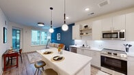 Located at 222 N West St in downtown Raleigh, NC, this thoughtfully designed one-bedroom, one-bathroom residence offers a well-organized, efficient layout across a single floor. Light wood-look flooring runs throughout, lending warmth and continuity to every room.

The open-concept kitchen, dining, and living area serves as the heart of the home. The kitchen is outfitted with white flat-front cabinetry, a white subway tile backsplash, a large waterfall-edge island with bar seating, globe pendant lighting, stainless steel appliances, and open wood shelving. The living area flows naturally from the kitchen and is anchored by a bold teal accent wall, large windows that invite natural light, and access to a private balcony with urban views.

The bedroom is a calm retreat with neutral white walls, a ceiling fan, and a window with natural light. It is accompanied by a well-appointed walk-in closet featuring built-in shelving, hanging rods, and a dedicated drawer unit—providing generous storage.

The bathroom features a single vanity with an LED-backlit mirror, white subway tile surround, a soaking tub with shower, and clean, bright finishes. Additional conveniences include an in-unit laundry area and a utility room. Two closets further enhance the storage capacity of this well-appointed Raleigh residence.