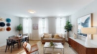 This single-floor residence at 3818 Page Rd in Durham, NC offers a thoughtfully designed open layout with a clean, contemporary aesthetic. The living area is filled with natural light streaming through multiple large windows dressed in sheer white curtains and shutters, illuminating warm hardwood-style flooring and soft neutral tones. A defined dining area sits adjacent to the living space, providing a natural flow for daily living and entertaining.

The kitchen is a standout feature, boasting white shaker cabinetry, sleek white countertops, stainless steel appliances, and a central island with bar seating highlighted by pendant lighting — ideal for casual meals or social gatherings. Ample pantry and storage space add practical convenience.

The bedrooms offer a calm retreat, featuring plush carpeting, generous natural light, and stylish details. One bedroom includes a distinctive sliding barn door that opens to a hallway with closet access, adding a modern architectural touch. The bathroom features a white vanity with clean lines, a large mirror, hardwood-style flooring, and an adjacent walk-in closet with built-in shelving for organized storage.

Throughout the home, the consistent use of soft gray walls, warm wood tones, and light-filled spaces creates a cohesive and welcoming ambiance well-suited to comfortable everyday living in Durham.