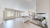 This single-floor residence in Folsom, California offers a thoughtfully designed open-concept layout filled with natural light. The kitchen serves as the heart of the home, showcasing white cabinetry with brushed nickel hardware, dark quartz countertops, stainless steel appliances including a gas range, built-in microwave, dishwasher, and French door refrigerator with ice and water dispenser. A central island provides additional prep and dining space, while light wood-look flooring extends seamlessly into the generous living area. Large windows and a glass door open to a balcony, inviting abundant natural light and outdoor views into the main living space. The bedrooms feature neutral carpeting, ceiling fans, and multiple windows that brighten each room. At least one bedroom includes a walk-in closet with built-in shelving, adding practical storage. The bathroom is well-appointed with a wide vanity, dark quartz countertops, white cabinetry, a large mirror, and a full tub-shower combination with tile surround and tile flooring. In-unit laundry is also present, contributing to the home's functional and move-in ready design.