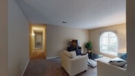 This single-story residence offers a well-organized layout with distinct living, dining, kitchen, bedroom, and laundry areas, all finished in a consistent warm neutral palette. The living room is generously proportioned, featuring carpet flooring, a textured ceiling, and an arched window that draws in natural light. The space flows openly toward a separate dining area, which is accented by hardwood-style flooring and a pendant light fixture overhead, providing an inviting setting for gatherings.

The galley-style kitchen is equipped with white cabinetry, white appliances including a refrigerator and range, a stainless steel sink, and light wood-style flooring, offering a clean and functional cooking environment. Conveniently adjacent to the kitchen, a dedicated laundry alcove houses a full-sized washer and dryer alongside built-in shelving for storage.

The bedrooms are carpeted and finished with neutral walls and textured ceilings. The primary bedroom includes a ceiling fan, ample space, and access to a connecting area. Additional bedrooms provide comfortable, quietly appointed spaces. The bathroom features a tiled tub-shower combination. A hallway connects the private areas of the residence, completing a practical and cohesive floor plan.