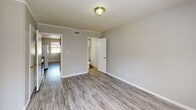 Located at 600 Folmar St in Troy, Alabama, this single-story one-bedroom, one-bathroom unit offers a practical and efficiently designed layout. Throughout the space, gray luxury vinyl plank flooring provides a clean, cohesive look, complemented by light gray walls and white trim.

The open kitchen area is equipped with gray shaker-style cabinetry, a tile backsplash, an electric range, and a full-size white refrigerator. The kitchen flows naturally into the main living area, creating an open and functional space despite its compact footprint.

The bedroom is the largest room in the unit, featuring vertical shiplap-style wall paneling in gray, a textured ceiling, and a window that allows natural light to fill the space. Two interior doors provide access to additional storage or utility areas, adding to the room's practicality.

The bathroom includes a standalone walk-in shower stall with a chrome showerhead and ventilation fan overhead, offering a clean and straightforward design.

Throughout the unit, flush-mount light fixtures with gold accents provide consistent lighting. The textured ceilings and neutral color palette create a simple, low-maintenance living environment well-suited for those seeking functional and affordable housing in Troy, AL.
