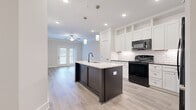 Located at 5025 Pilatus Way in Mebane, NC, this well-appointed 2-bedroom, 2-bathroom single-story home offers a thoughtfully designed layout with modern finishes throughout. The open-concept kitchen is a standout feature, showcasing white shaker cabinetry, subway tile backsplash, stone countertops, and a center island with a built-in sink, open shelving, and pendant lighting. Black appliances, including a gas range and refrigerator, complement the clean aesthetic. The kitchen flows seamlessly into the living area, which features light wood-look flooring, recessed lighting, a ceiling fan, and a set of French doors that invite natural light. The two bedrooms are carpeted and generously sized, each with multiple windows that brighten the space and ceiling fans for comfort. The primary bedroom is notably spacious. Both bathrooms are finished with wood-look vinyl flooring, white cabinetry, dark granite countertops, and tub-shower combinations. The hallways connect the layout efficiently, while a dedicated closet adds practical storage. Throughout the home, neutral tones, clean lines, and consistent finishes create a cohesive and contemporary ambiance suited to a variety of lifestyles.