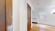 Located at 16 Chapel Road in Buffalo, NY, this well-appointed single-floor, one-bedroom, one-bathroom unit offers a thoughtfully designed layout with a clean, updated aesthetic. Warm hardwood flooring runs consistently throughout, lending a sense of cohesion and character to the space.

The combined kitchen and living area forms the heart of the unit. The kitchen is outfitted with crisp white shaker-style cabinetry, light stone countertops, and a full suite of stainless steel appliances including a refrigerator, electric range with a wall-mounted range hood, and dishwasher. An elegant arched passageway connects the kitchen area to the living space, adding a classic architectural touch.

The living room benefits from natural light through slatted blinds and offers an open, airy feel. The generously sized bedroom features multiple windows with views of surrounding greenery, wall sconces, and a flush-mount ceiling light, creating a calm and comfortable retreat. A secondary room provides additional flexible space, complete with baseboard heating and a window.

The bathroom is finished in white tile, featuring a soaking tub with shower, a pedestal sink, and a window for natural ventilation. Crown molding is present throughout, reinforcing the home's classic character. The entrance provides a welcoming transition into the unit.