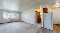 This single-floor unit offers a practical and well-organized layout, comprising one bedroom, two bathrooms, a kitchen, and a connecting hallway. The living area features neutral-toned carpet and white walls accented by warm wood trim, creating a clean and cohesive aesthetic. A window with a wall-mounted AC unit allows natural light to filter in, while a baseboard heating system runs along the perimeter, ensuring year-round comfort.

The bedroom is a comfortable, carpeted space with its own window fitted with vertical blinds, offering outdoor views and natural light. A baseboard heater runs beneath the window, and the room connects conveniently to the hallway.

The kitchen is efficiently designed with warm oak cabinetry both above and below the counters, a granite-style laminate countertop, a double-basin sink, and wood-look vinyl flooring. White appliances complement the cabinetry and contribute to a bright, functional workspace.

Both bathrooms feature oak vanities with granite-style countertops and large mirrors. One bathroom includes a full tub-shower combination with wood-look vinyl flooring, while the second bathroom serves as an additional vanity space. Throughout the unit, consistent use of warm wood-toned trim and doors ties the overall design together cohesively.
