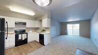 Located in Vancouver, WA, this single-floor, 2-bedroom, 2-bathroom residence offers a practical and comfortable layout. The living room is spacious and carpeted, featuring neutral gray walls and a sliding glass door that fills the space with natural light while providing outdoor access. The kitchen is well-appointed with white cabinetry, light countertops, wood-look vinyl flooring, and black appliances including a range, refrigerator, and dishwasher, all illuminated by overhead lighting. Both bedrooms are carpeted and finished with neutral tones, each featuring sliding closet doors that maximize floor space. Windows in each bedroom allow for natural light and views of the surrounding greenery. The two bathrooms are consistently designed with wood-look vinyl flooring, white cabinetry, taupe countertops, large vanity mirrors, and tub-shower combinations with tile surrounds. A connecting hallway ties the layout together efficiently. Baseboard heating is present throughout the unit. The overall aesthetic is clean and understated, with a neutral color palette that creates a calm, move-in-ready environment suitable for a variety of living arrangements.