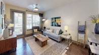 This thoughtfully designed single-floor residence offers a contemporary living experience with a cohesive aesthetic carried throughout each space. The open-concept kitchen is a standout feature, equipped with stainless steel appliances including a gas range, over-the-range microwave, and French door refrigerator. Sleek, textured cabinetry in a warm grey tone pairs with dark granite countertops and a subway tile backsplash, while a peninsula with seating for two and pendant lighting above adds both function and style. Rich polished concrete flooring flows seamlessly through the entire unit, lending an urban, modern character to every room. The living area is bright and welcoming, benefiting from generous natural light through large windows with outdoor views, and features a ceiling fan and direct access to a private outdoor space. Two well-proportioned bedrooms each offer large windows that invite natural light, providing a comfortable and airy retreat. The bathroom is efficiently laid out with a wide vanity, a large mirror with integrated lighting, a tub-shower combination, and ample storage. A dedicated closet area adjacent to the bathroom adds additional organizational convenience. The overall ambiance is modern and curated, with clean lines and contemporary finishes throughout.