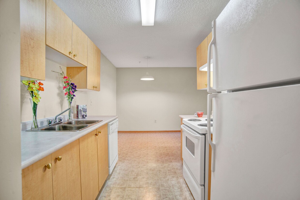 A kitchen with white appliances and light cabinetry - Wellington Manor