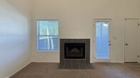 This two-story, 1-bedroom, 1-bathroom residence offers 940 square feet of well-organized living space, with 540 square feet on the ground floor and 400 square feet on the upper level. The main floor hosts a combined kitchen and living room area, where the living space features a tile-surround fireplace, carpet flooring, and windows with blinds that allow ample natural light. A door adjacent to the fireplace provides additional access. The kitchen is thoughtfully updated with dark cabinetry, white countertops, a subway tile backsplash, recessed lighting, and stainless steel appliances including a refrigerator, over-the-range microwave, and electric range. Light wood-look flooring completes the kitchen's modern aesthetic. A staircase leads to the upper level, which accommodates the 110-square-foot bedroom featuring carpet flooring, a textured ceiling, and a window overlooking greenery. Two closets provide dedicated storage on this floor. The full bathroom includes a dark vanity with a white countertop, a framed mirror, and a combined tub/shower. The unit's neutral color palette and functional two-floor layout make it a practical and comfortable living space.