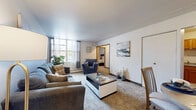 Located at 3141 S 77th St in Milwaukee, Wisconsin, this one-bedroom, one-bathroom unit offers a practical and well-organized single-floor layout. The living room features neutral-toned carpet flooring, a baseboard heating unit, and a large window that allows natural light to fill the space, creating a bright and welcoming atmosphere. Wall art accents add a touch of personality to the clean, light-colored walls. Adjacent to the living room, a dedicated dining area provides a defined space for meals, highlighted by a decorative starburst wall accent overhead. A connecting hallway leads seamlessly to the private bedroom, which is carpeted and comfortably sized, offering a closet with wooden sliding doors and ample room for standard furnishings. The full bathroom includes a tiled tub-shower combination with a curtain rod, a toilet, and a clean, functional design with classic square wall tiling. Throughout the unit, baseboard heating is consistently present, ensuring comfort year-round. The overall ambiance is understated and practical, with neutral tones, carpeted floors, and a cohesive layout that makes efficient use of every square foot — ideal for those seeking a straightforward and manageable living space in the Milwaukee area.