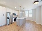 Located at 370 Carmelina Ave in Columbus, Ohio, this well-designed 2-bedroom, 1-bathroom home offers a thoughtfully laid-out single floor with modern finishes throughout. Light-toned hardwood-style flooring flows seamlessly across every room, creating a cohesive and inviting atmosphere.

The kitchen serves as the centerpiece of the home, featuring a large central island with a white quartz countertop, an undermount sink with a matte black faucet, and stylish globe pendant lights with brass accents. White shaker-style cabinetry extends to the ceiling for ample storage, complemented by a subway tile backsplash and a full suite of stainless steel appliances. Natural light pours in through a large window, enhancing the open and airy feel of the space.

The primary bedroom is generously proportioned, boasting multiple windows that bring in abundant natural light and views of the surrounding neighborhood. The second bedroom is bright and well-sized, also featuring a window and light neutral walls. Both bedrooms include closet access.

The bathroom is elegantly finished with a double-sink white vanity, white quartz countertops, and black hardware accents, topped by a gold-toned light fixture and a large mirror. The hallway connecting the rooms is clean and uncluttered, maintaining the home's modern, minimal aesthetic throughout.