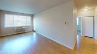 Located at 660 Columbia Point Dr in Richland, Washington, this single-floor residence offers a clean, modern aesthetic throughout. The open living area features warm hardwood-style flooring that reflects natural light streaming in through large windows, creating a bright and welcoming atmosphere. A private entry door leads into the spacious main living space, which flows seamlessly toward the kitchen.

The kitchen is well-equipped with stainless steel appliances, including a refrigerator, electric range, and over-the-range microwave. White cabinetry with ample storage lines the walls, complemented by light countertops and a stainless steel sink. Track lighting overhead ensures excellent task illumination throughout the cooking space. A peninsula provides additional prep space and separates the kitchen from the living area.

The bedroom is generously sized, featuring plush wall-to-wall carpeting and a ceiling fan for year-round comfort. Large windows fitted with blinds invite natural light while offering privacy, and views of the surrounding greenery and neighborhood are visible from multiple vantage points.

The overall design emphasizes a neutral color palette of soft whites and warm grays, clean lines, and functional layouts, making the space feel open, airy, and move-in ready.