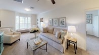 This single-floor, two-bedroom, two-bathroom residence offers a thoughtfully designed layout that balances comfort and functionality. The living room is a welcoming, generously sized space featuring crown molding, a ceiling fan, plush carpeting, and multiple windows that fill the room with natural light. The open sightline toward the kitchen and dining area creates a seamless flow, ideal for everyday living and entertaining.

The kitchen is well-equipped with rich dark cabinetry, granite-style countertops, wood-look flooring, track lighting, and a full suite of white appliances including a refrigerator, dishwasher, and range. Ample cabinet and counter space make this kitchen both practical and visually appealing.

Both bedrooms are generously proportioned with plush carpet, crown molding, and ceiling fans. The primary bedroom features a distinctive bay window that lets in abundant natural light and includes access to a walk-in closet. The secondary bedroom also offers a walk-in closet and a large window with outdoor views.

Each bathroom is finished with wood-look flooring, dark cabinetry with granite-style countertops, and a tub-shower combination. The clean, neutral palette throughout both bathrooms contributes to a calm, functional atmosphere. Together, these spaces form a cohesive and comfortable residence.