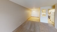 This single-floor unit offers a well-organized layout across three bedrooms and two bathrooms, providing a comfortable and functional living environment. The living room is generously sized, featuring wall-to-wall carpeting, a baseboard heating system, and a sliding glass door that opens to a private outdoor balcony — bringing in natural light and outdoor views of surrounding greenery. A wall-mounted air conditioning unit adds year-round climate control convenience.

The dining area connects smoothly to the living space, finished with parquet-style flooring and accented by a chandelier overhead. It flows directly into the kitchen, which features white cabinetry with wood trim, light-toned laminate countertops, a double stainless steel sink, an electric range with overhead ventilation, and a refrigerator — all set on easy-care tile flooring.

Each of the three bedrooms is carpeted and includes a baseboard heater and a window offering outdoor views. The two bathrooms are functional in design; one features a vanity with a granite-style countertop, a medicine cabinet, and tile flooring, while the second is compact and straightforward. Textured ceilings are consistent throughout the unit, contributing to its classic, practical character.