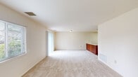 This single-floor residence offers a practical and comfortable layout across a well-utilized footprint. The open living area serves as the heart of the home, featuring plush wall-to-wall carpeting, neutral cream-toned walls, and generous natural light streaming in through a sliding glass door that opens to an outdoor view of greenery — creating a bright and airy atmosphere. A secondary window further enhances the light-filled feel of the space.

The kitchen is thoughtfully designed with warm wood-toned cabinetry spanning both upper and lower storage, white appliances including an electric range and refrigerator, a single-basin sink, and light wood-look flooring. A peninsula counter connects the kitchen to the living area, offering additional prep or serving space.

The bedroom is a comfortable, carpeted retreat featuring a natural light window with blinds and a closet equipped with a rod and shelving for organized storage.

The bathroom is clean and efficiently laid out, with wood-look flooring, a white vanity with under-cabinet storage, a lighted mirror, toilet, and a shower-tub combination. A utility room completes the home, providing additional functional space. Overall, this residence offers a clean, neutral palette and a sensible layout suited for everyday living.
