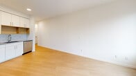 Located at 4603 Minnehaha Ave in the vibrant Longfellow neighborhood of Minneapolis, Unit 207 is a thoughtfully designed single-floor residence that maximizes its compact footprint with a clean, modern aesthetic throughout. Light wood-tone flooring runs continuously across the space, complementing the crisp white walls and creating a bright, cohesive atmosphere.

The kitchen is a functional highlight, featuring white cabinetry with ample upper and lower storage, gray countertops, a subway tile backsplash, and a warm wood-toned open shelving accent. Stainless steel appliances — including a range, dishwasher, microwave, and refrigerator — complete the well-appointed cooking space.

The open living area is bathed in natural light from large, floor-to-ceiling style windows that frame outdoor views of the surrounding neighborhood. The space offers a flexible layout suitable for both lounging and dining arrangements.

A narrow hallway connects the living areas to the bathroom, which is equipped with a glass-door stand-up shower with brushed nickel fixtures, a built-in open shelving unit for storage, a toilet, and a vanity. Recessed ceiling lighting throughout adds to the clean, well-lit ambiance of the unit.

Overall, Unit 207 presents a modern, minimalist living environment ideal for those seeking a streamlined and efficiently designed urban residence in Minneapolis.