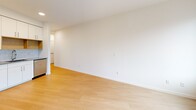 Located at 4603 Minnehaha Ave in the vibrant Longfellow neighborhood of Minneapolis, Unit 207 is a thoughtfully designed single-floor residence that maximizes its compact footprint with a clean, modern aesthetic throughout. Light wood-tone flooring runs continuously across the space, complementing the crisp white walls and creating a bright, cohesive atmosphere.

The kitchen is a functional highlight, featuring white cabinetry with ample upper and lower storage, gray countertops, a subway tile backsplash, and a warm wood-toned open shelving accent. Stainless steel appliances — including a range, dishwasher, microwave, and refrigerator — complete the well-appointed cooking space.

The open living area is bathed in natural light from large, floor-to-ceiling style windows that frame outdoor views of the surrounding neighborhood. The space offers a flexible layout suitable for both lounging and dining arrangements.

A narrow hallway connects the living areas to the bathroom, which is equipped with a glass-door stand-up shower with brushed nickel fixtures, a built-in open shelving unit for storage, a toilet, and a vanity. Recessed ceiling lighting throughout adds to the clean, well-lit ambiance of the unit.

Overall, Unit 207 presents a modern, minimalist living environment ideal for those seeking a streamlined and efficiently designed urban residence in Minneapolis.