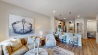 Located at 4711 Azalea Landing Dr in Wilmington, NC, this well-appointed one-bedroom, one-bathroom residence offers a cohesive coastal aesthetic throughout its efficiently organized single-floor layout. Light wood-tone flooring flows seamlessly through every room, complementing the soft neutral palette that defines the space.

The open-concept living and kitchen area serves as the heart of the home. The living room features recessed lighting, a large wall-mounted TV, and a generous window that invites natural light and outdoor views. The kitchen is highlighted by a substantial granite-topped island with bar seating for multiple guests, sleek white and wood cabinetry, stainless steel appliances, and stylish pendant lighting overhead.

A built-in desk nook with granite surface adjacent to the bedroom hallway provides a dedicated workspace. The bedroom is comfortably sized, featuring a walk-in closet, ceiling fan, and large windows with natural views. The full bathroom includes a wood-toned vanity with granite countertop, a large framed mirror with black hardware accents, and a tiled combination tub and shower.

A dedicated laundry area houses a full-size front-loading washer with overhead shelving for added storage. Throughout the space, coastal-themed artwork reinforces a relaxed, seaside-inspired atmosphere.
