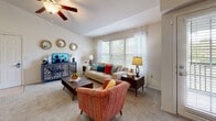 Located at 2001 W Princeton Cir in Broken Arrow, Oklahoma, this single-story residence offers a well-designed, open-concept layout that maximizes comfort and functionality throughout. The living room serves as the heart of the home, featuring a vaulted tray ceiling, a ceiling fan, and a generous bank of windows dressed with sheer curtains and blinds that flood the space with natural light and offer views of the surrounding greenery. Soft carpeting adds warmth underfoot throughout the main living areas and bedrooms. The kitchen is efficiently designed with rich warm-toned wood cabinetry, granite-style countertops, white appliances including a side-by-side refrigerator with water dispenser, and a peninsula with bar seating for two — ideal for casual dining or entertaining. Tile flooring in the kitchen provides a clean, practical surface. The bedrooms are comfortably sized, each featuring ceiling fans with light fixtures and windows that bring in natural light. The bathroom is well-appointed with a wide vanity topped with light counters, a large mirror, wood cabinetry for storage, and a tiled tub-shower combination. Throughout the home, a neutral color palette and consistent finishes create a cohesive and inviting atmosphere.
