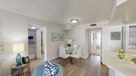 Located in Boca Colony in Boca Raton, Florida, this two-bedroom, single-floor residence offers a well-organized layout designed for comfortable everyday living. The living area features light wood-style flooring, a textured ceiling, and neutral walls that create a bright, airy atmosphere. A connected dining space accommodates a round table with seating for four, while natural light filters through the windows to enhance the open feel throughout.

The kitchen is outfitted with white shaker-style cabinetry, light countertops, and stainless steel appliances including a range, microwave, and dishwasher. A window above the sink allows additional natural light into the space, and the layout provides ample counter space for meal preparation.

Both bedrooms are carpeted and generously sized, each featuring a ceiling fan, natural light from windows, and closet storage. One bedroom features a bold navy accent wall paired with a closet, while the second bedroom offers a softer, neutral palette. The primary bedroom includes access to a walk-in closet and a well-appointed bathroom featuring a wide vanity with white cabinetry, a large mirror, and bright overhead lighting. The overall ambiance throughout the residence is clean, cohesive, and move-in ready.