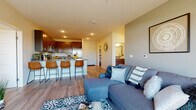 This thoughtfully designed single-floor residence offers a seamless blend of functionality and modern style throughout its well-planned layout. The open-concept living and dining area is anchored by warm wood-look plank flooring, recessed lighting, and a sliding glass door that leads to a private balcony with outdoor views, filling the space with natural light. Built-in shelving adds both character and practical storage to the living area.

The kitchen is a standout feature, showcasing rich dark-wood cabinetry, granite countertops, and a full suite of stainless steel appliances, including a refrigerator, range, and built-in microwave. A peninsula with seating for multiple bar stools creates a natural gathering point and connects the kitchen to the main living space.

The bedroom is a comfortable retreat, carpeted for warmth and featuring a window with views of the surrounding landscape. Adjacent to the bedroom is a sitting area with access to a walk-in closet, offering generous storage. The bathroom is finished with a dark-wood vanity topped with granite, tile flooring, and a shower-tub combination. A dedicated in-unit laundry area with a full-size washer and dryer adds everyday convenience, completing this well-rounded and move-in-ready residence.