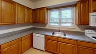 This two-story residence in Morris Plains, NJ offers a well-organized floor plan with three bedrooms and two and a half bathrooms. Warm-toned hardwood floors flow consistently throughout the main living areas and bedrooms, contributing to a cohesive and inviting aesthetic. The living area is spacious and open, with a staircase visible from the main level, connecting both floors seamlessly. A beam detail near the ceiling adds subtle architectural character to the lower level.

The kitchen features oak cabinetry with ample upper and lower storage, dark laminate countertops, a stainless steel sink, and a dishwasher. A window above the sink allows natural light and outdoor views into the space. The tile flooring in the kitchen provides a practical transition from the wood floors elsewhere.

The bedrooms are well-proportioned, with hardwood floors and sliding closet doors offering built-in storage. The primary bedroom includes multiple windows and a ceiling fan with integrated lighting. The full bathrooms feature warm-toned tile floors and walls, with one offering a tub-shower combination and another a glass-door shower stall. The half bath includes a wood-framed vanity and mirror, completing the home's functional layout.
