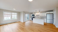 Located at 28 Hackamore in Scarborough, Maine, this single-floor residence offers a clean, modern design with an open-concept living and kitchen area that maximizes both functionality and flow. Light hardwood flooring runs throughout the main living spaces, complementing the neutral, warm-toned walls and crisp white trim.

The kitchen is a standout feature, equipped with white shaker-style cabinetry, granite countertops, a central island with additional seating and storage, stainless steel appliances — including a refrigerator, range, microwave, and dishwasher — and a stainless undermount sink. Stylish pendant lighting above the island adds a contemporary touch. A sliding glass door leads from the living area to a private balcony, while large windows invite abundant natural light and views of the surrounding community.

The bedrooms are carpeted for comfort and each features windows with blinds, baseboard heating, and generous closet space. A dedicated storage or utility area with hardwood flooring adds practical value. Additional climate control is provided by a wall-mounted mini-split unit. The overall aesthetic is bright, clean, and move-in ready, reflecting thoughtful, modern construction suited for comfortable everyday living in the Scarborough community.