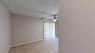 Located at 3803 Cotswold Ave in Greensboro, NC, this single-floor, 2-bedroom, 2-bathroom unit offers a practical and comfortable layout. The living room serves as the heart of the home, featuring a wood-burning fireplace, a ceiling fan with light, soft carpet underfoot, and a sliding glass door that opens to a private balcony with tree-lined views. A pass-through granite countertop bar connects the living area to the kitchen, which is appointed with white shaker-style cabinetry, granite countertops, light wood-style flooring, and black appliances including a refrigerator, range, and dishwasher. A louvered closet door provides additional storage within the kitchen area. Both bedrooms are carpeted and feature neutral gray walls, natural light from windows with blinds, and louvered bi-fold closet doors. The primary bedroom is a well-proportioned retreat. The two bathrooms include granite-topped vanities with white cabinetry and wood-style flooring; one bathroom features a full tub-shower combination. Clean finishes, consistent neutral tones, and thoughtful storage throughout make this a well-organized and move-in-ready space.
